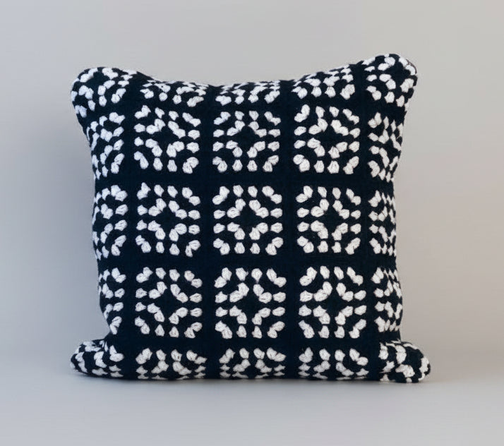 Black and white geometric crochet cushion on a light gray background