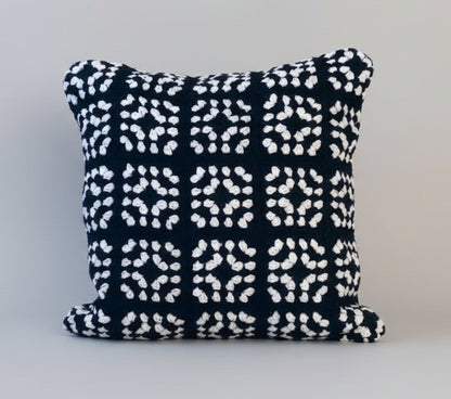 Black and white geometric crochet cushion on a light gray background