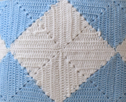 Close-up of a crocheted blanket with diamond pattern in white and blue sold by jess & pegg.
