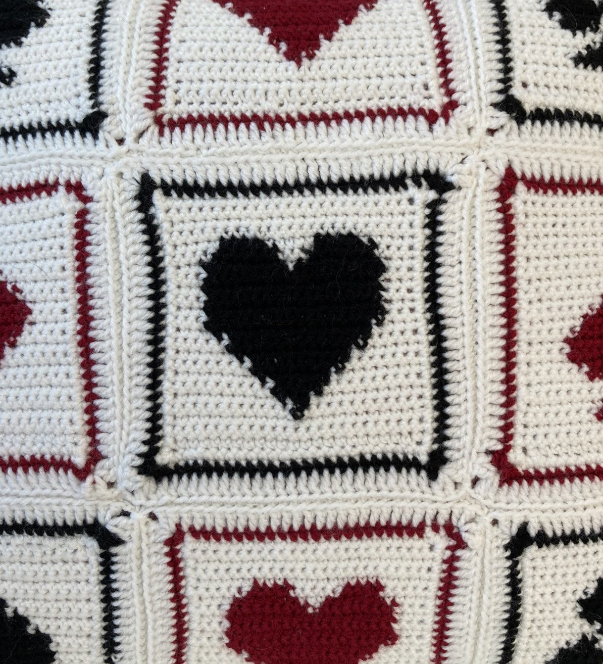 just cushions close up of crochet cushion with a black red and white playing cards pattern