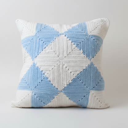Crocheted pillow with blue and white diamond pattern on a light grey background