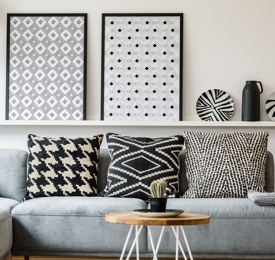 black and white cushions on a grey sofa with monochrome art on a white wall